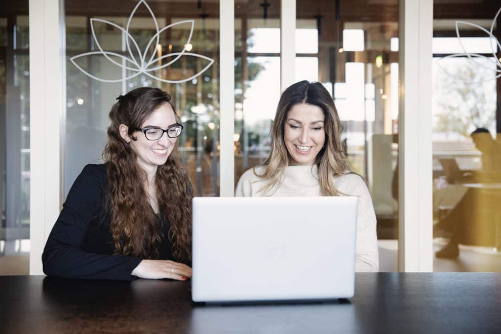 Twee collega's werken samen achter een laptop.